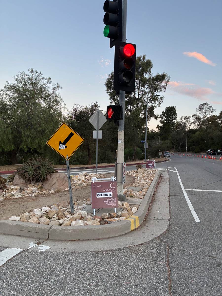 Directional open house sign placed in the hills at sunset