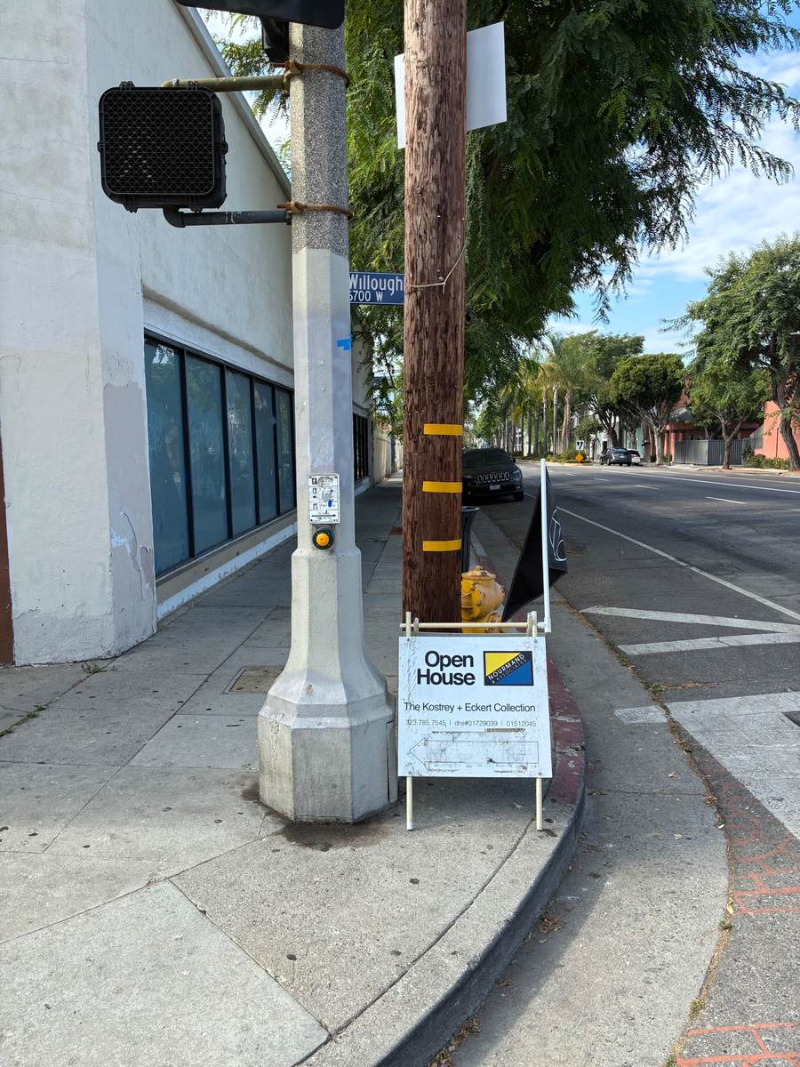 Open house directional sign placed at a city street corner